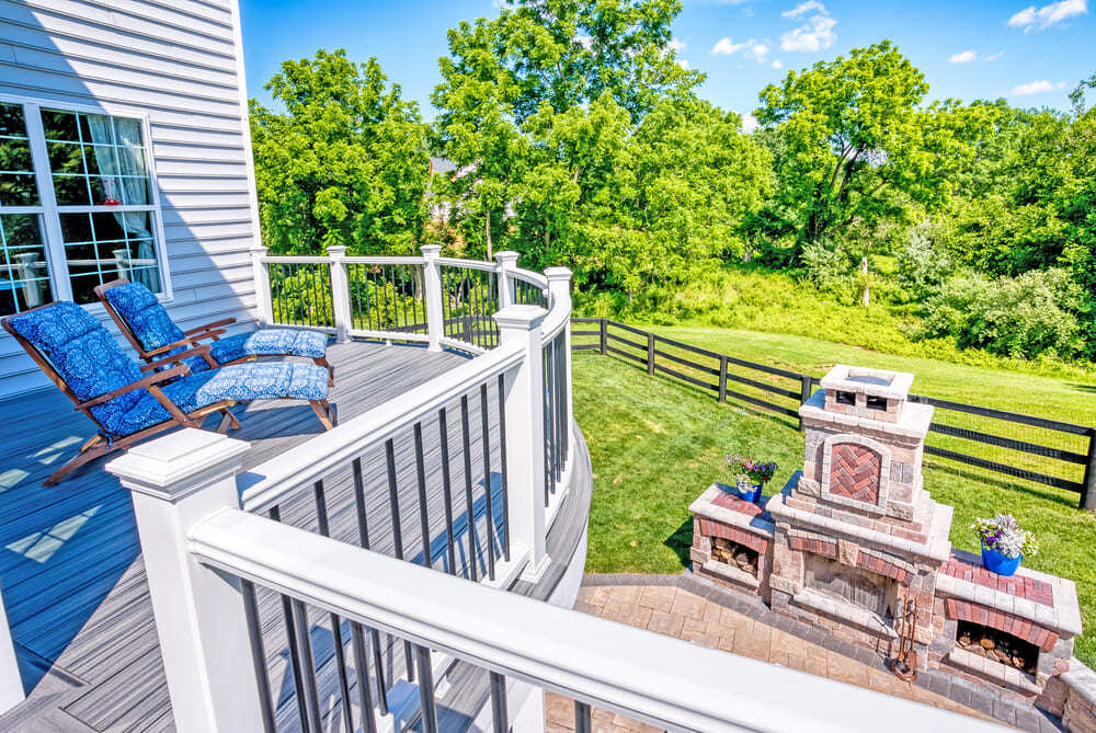 Curved Trex deck and railing above patio by Deckscapes of Virginia