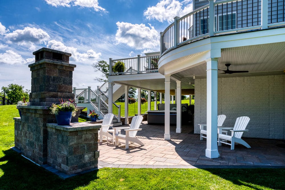 Curved Trex deck and under deck patio space with fireplace by Deckscapes of Virginia