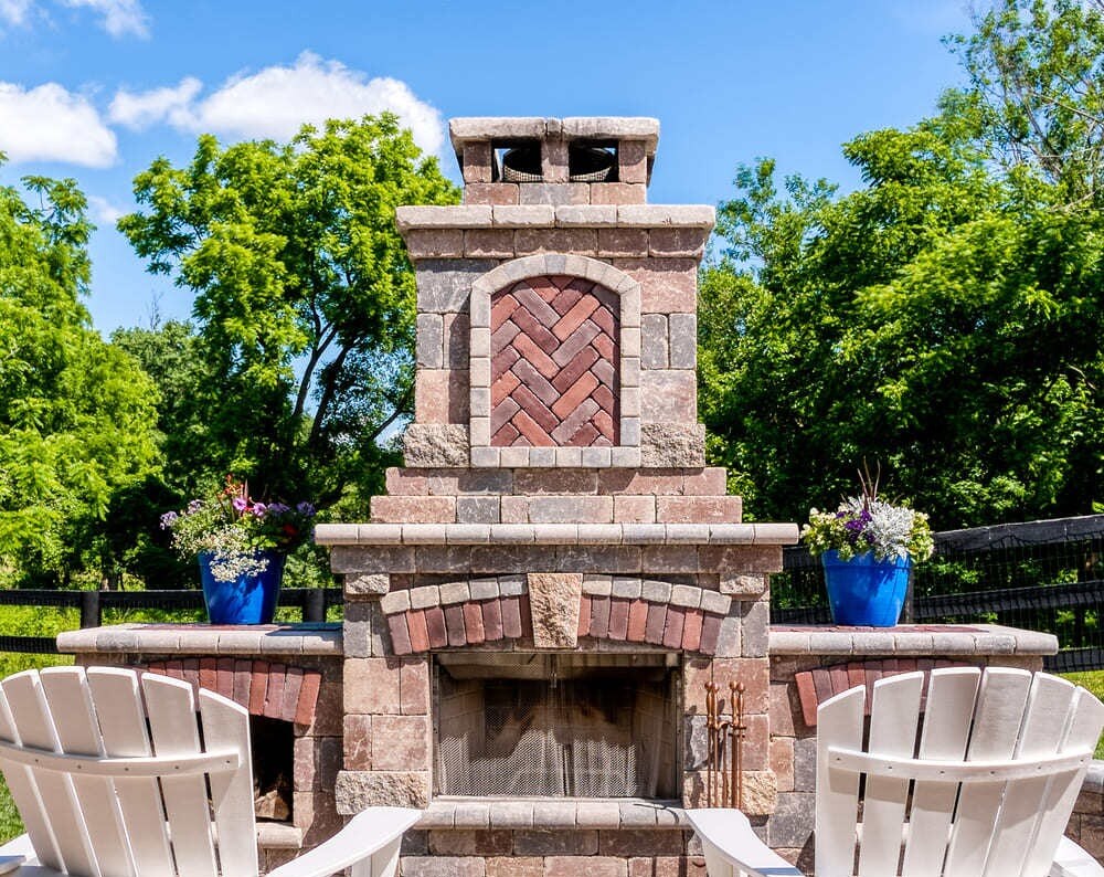 Fireplace on patio with log storage and herringbone pattern by Deckscapes of Virginia