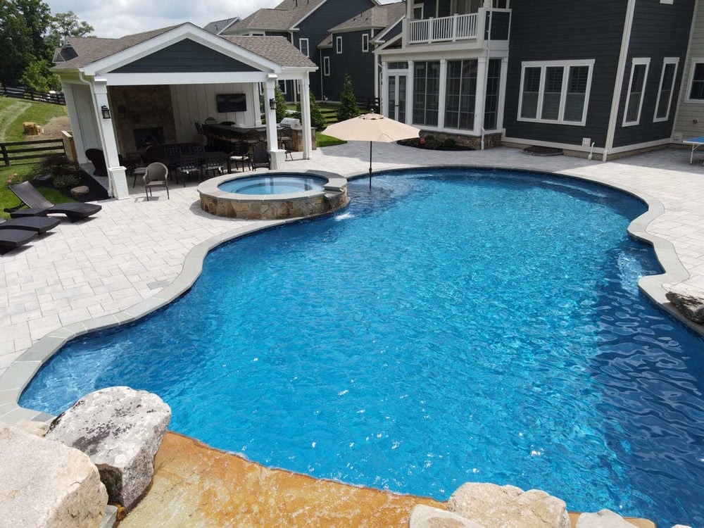 Freeform pool with spa next to pavilion by Deckscapes of VA