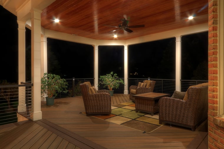 Covered deck at night with recessed lighting and ceiling fan by Deckscapes