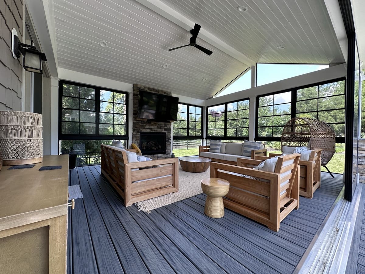 Covered patio with furniture and floor-to-ceiling windows by Deckscapes of VA