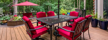 Custom deck with outdoor furniture and red accents by Deckscapes of VA