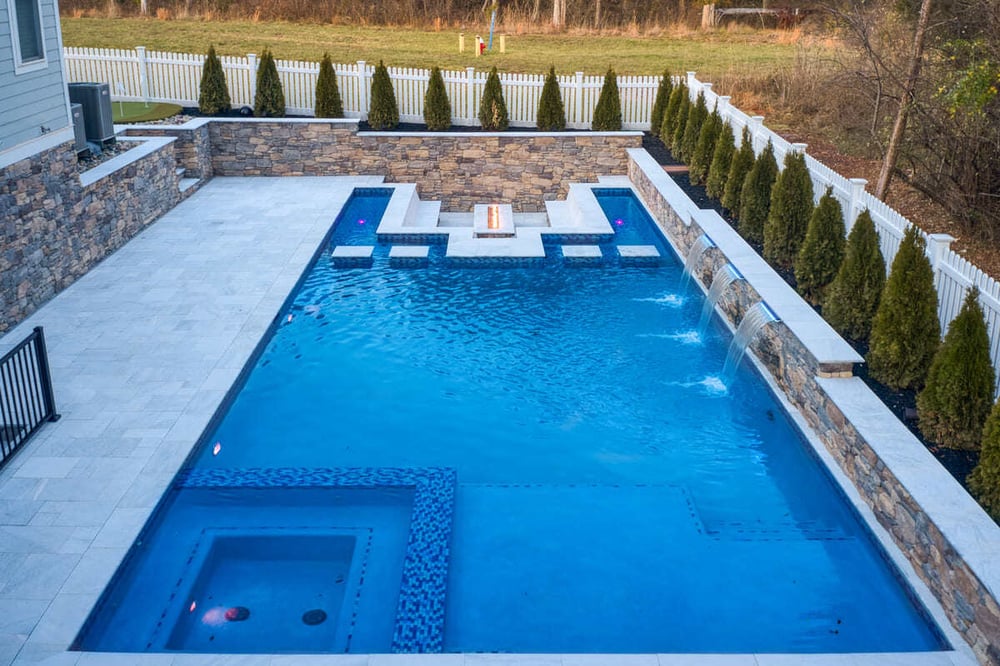 Custom gunite pool with in-ground fire pit and water feature by Deckscapes of VA