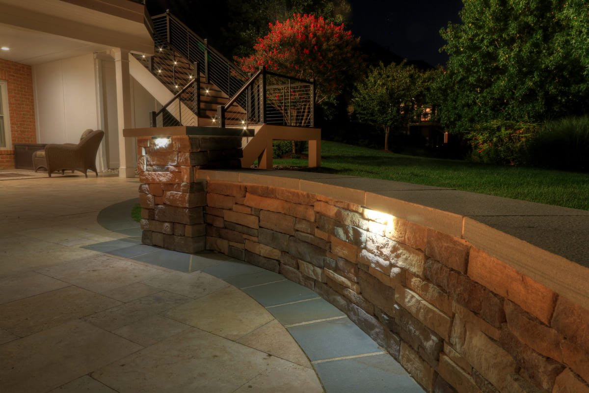 Custom lighting in stone retaining wall on patio by Deckscapes of Virginia