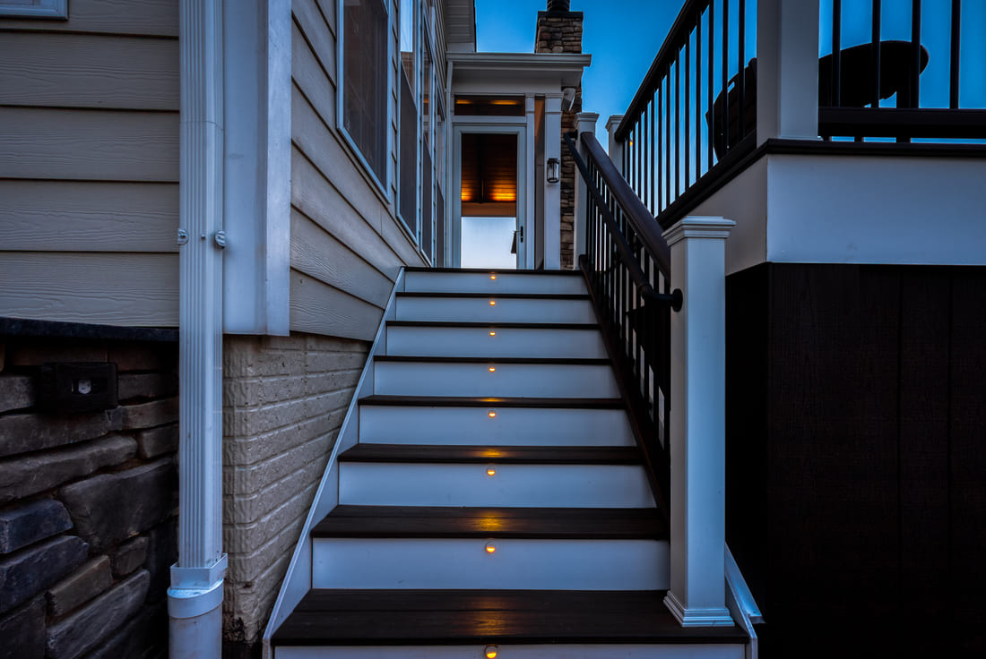 Custom lighting on deck staircase at dusk by Deckscapes of VA