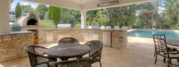 Custom outdoor kitchen built in under deck with stone oven by Deckscapes of Virginia