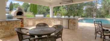 Custom outdoor kitchen built in under deck with stone oven by Deckscapes of Virginia