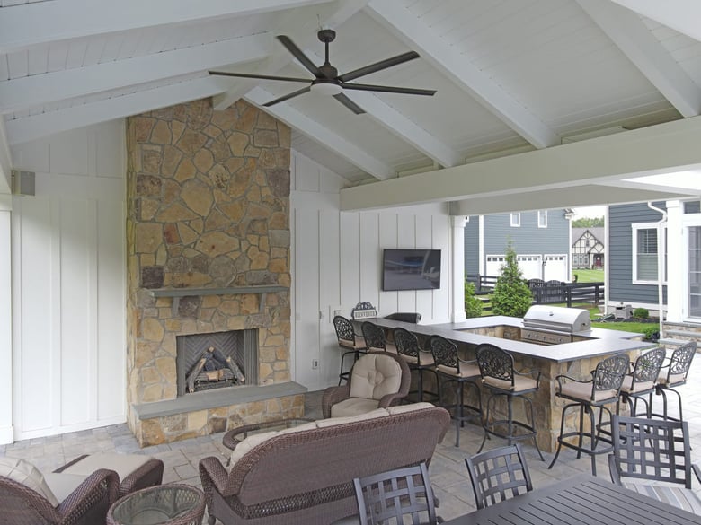 Custom pool house interior with fireplace and outdoor kitchen by Deckscapes of Virginia
