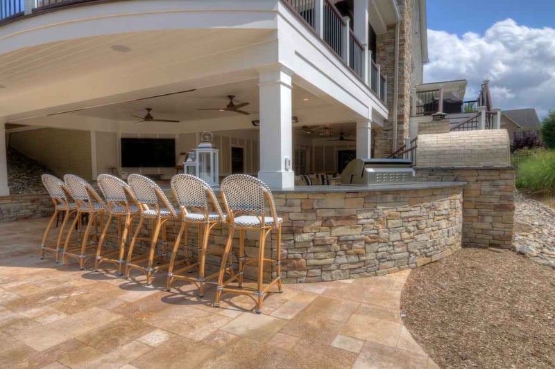 Custom outdoor kitchen and patio with curved stone wall