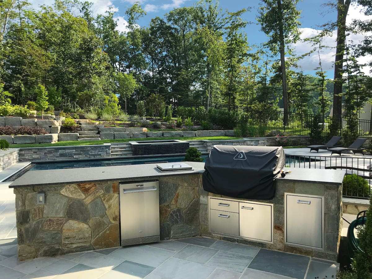 Custom outdoor kitchen on patio with stainless steel drawers and grill