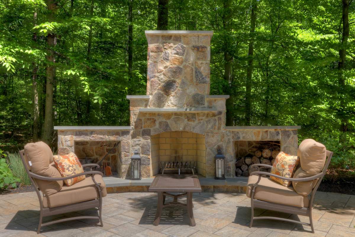 Stone fireplace built on patio with built in log storage