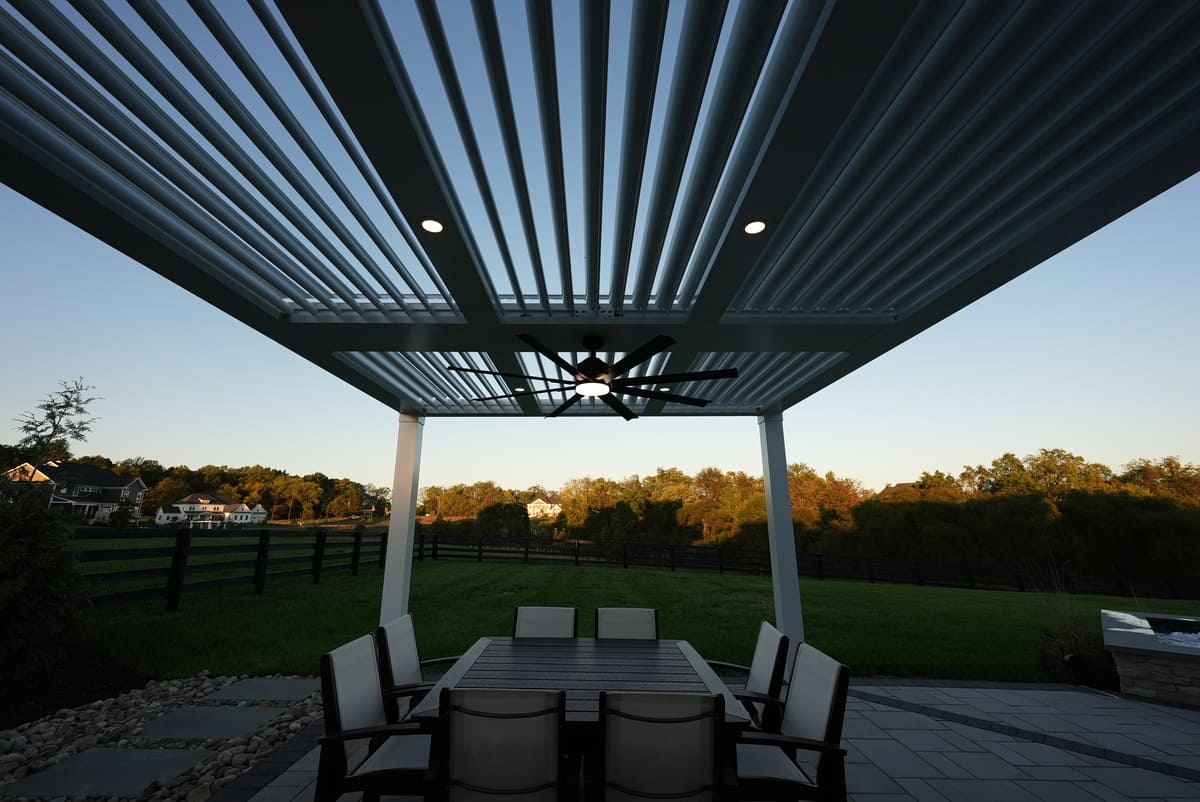 slatted pergola with fan and lighting, seating underneath, at twilight by Deckscapes of Virginia