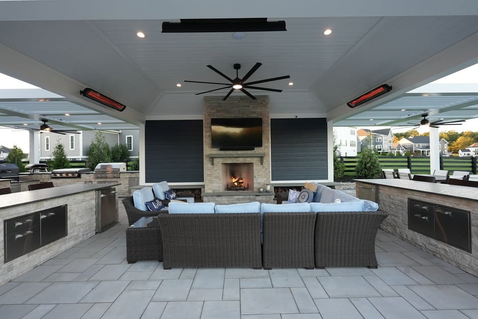 covered patio with outdoor kitchen, fan, seating, fireplace, and heaters in VA by Deckscapes