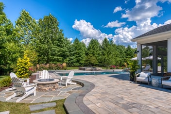 Patio and chairs by fireplace with gunite pool in back by Deckscapes of VA