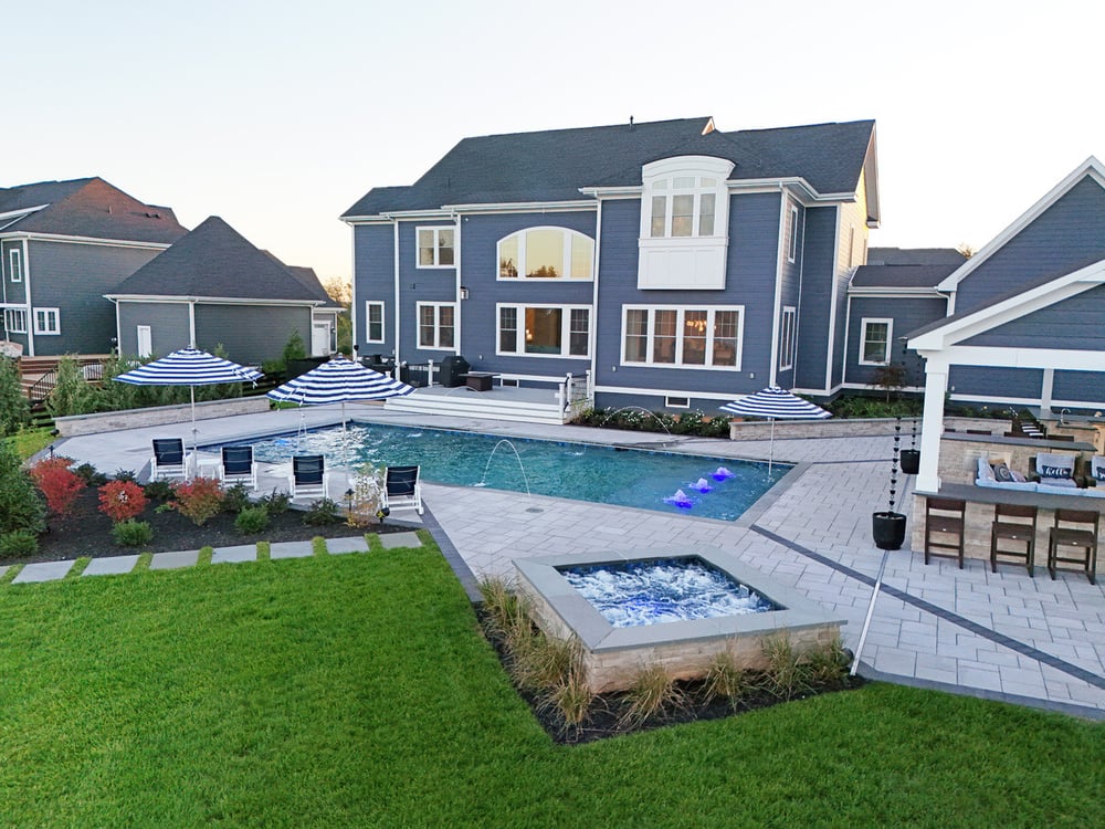 Pool, patio, and pool house design at sunset by Deckscapes of Virginia