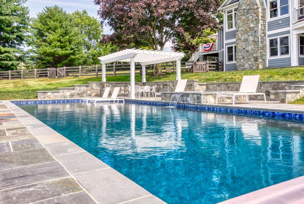 Gunite pool with waterfall feature and tanning ledge by Deckscapes of Virginia