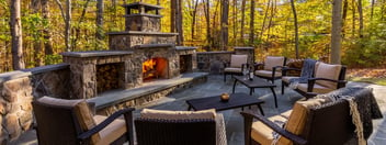 High-end stone fireplace on patio with log storage by Deckscapes of Virginia