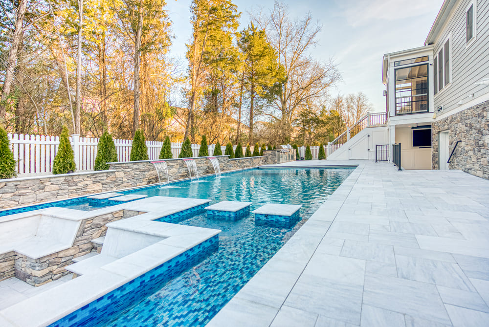 In-ground gunite pool on sunny day with marble pavers by Deckscapes of Virginia
