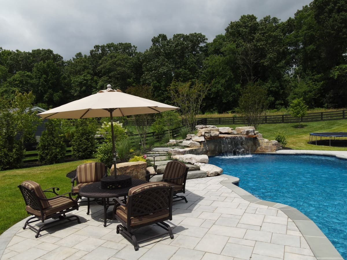 Landscaping around freeform pool with waterfall feature by Deckscapes of VA