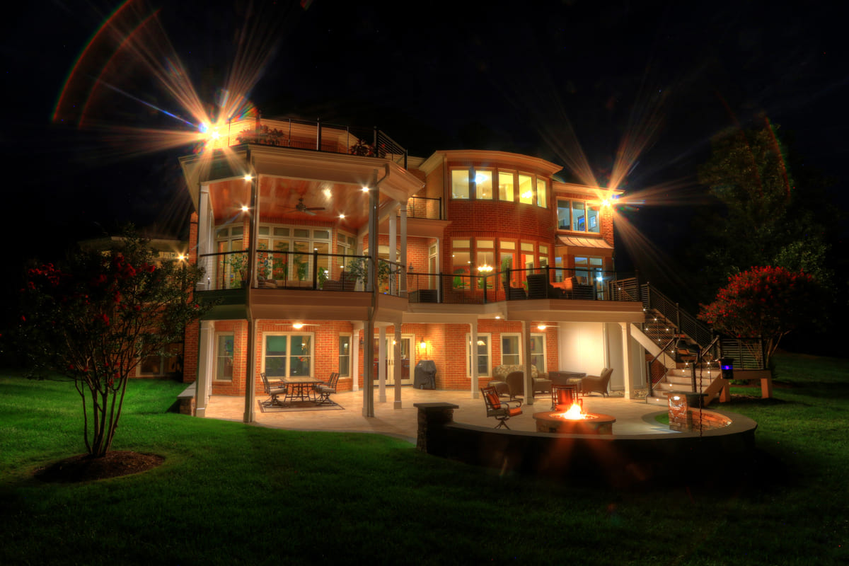 Leesburg, Virginia backyard exterior at night with patio and deck and custom lighting by Deckscapes of Virginia