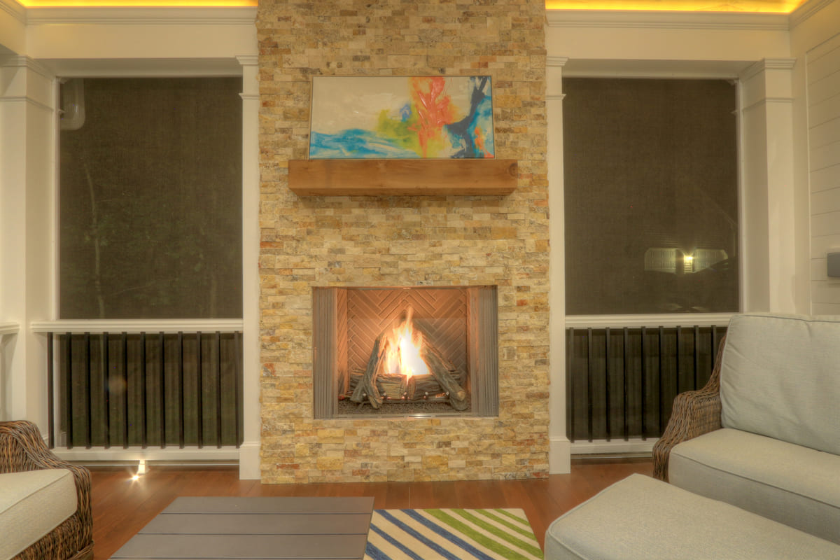 Lit fireplace in screened-in porch by Deckscapes of Virginia