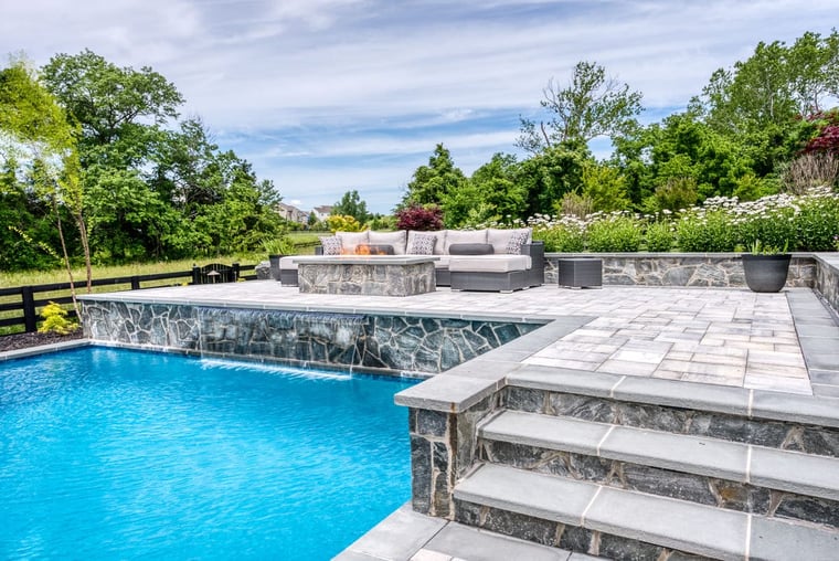 Luxury in-ground pool by Deckscapes of Virginia with stone waterfall feature