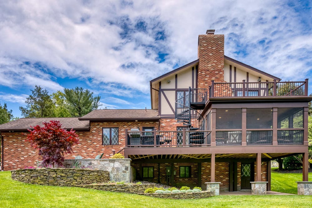 Multi-level outdoor living space with porch, deck, and patio by Deckscapes of VA