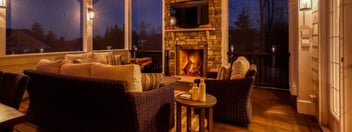 Interior view of screened-in porch at night with fireplace on below mounted TV