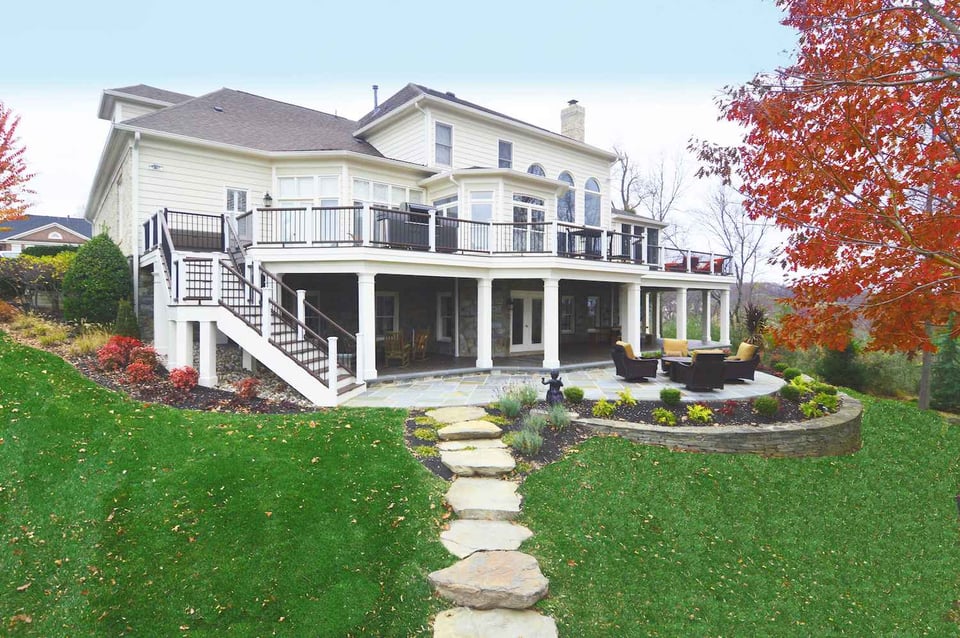 Two-story home with large deck and patio in Northern Virginia featuring black railing and stonework