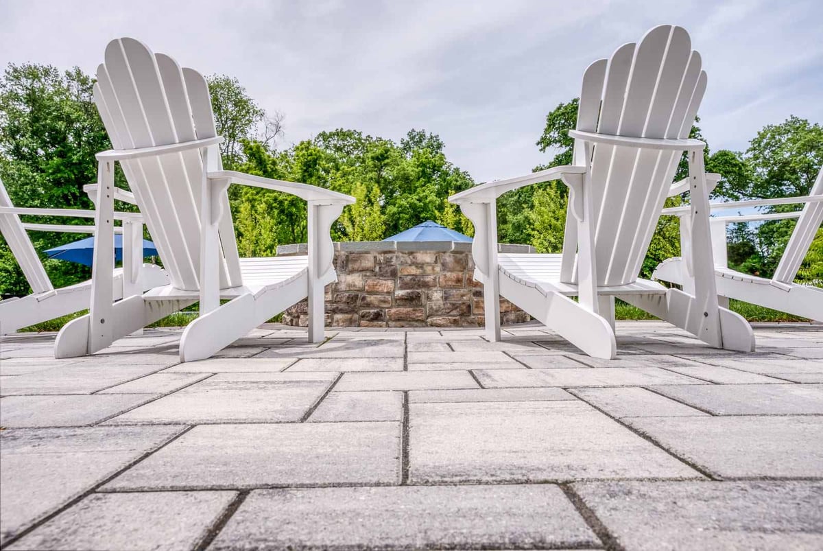 Concrete patio detailing with two white adirondack chairs