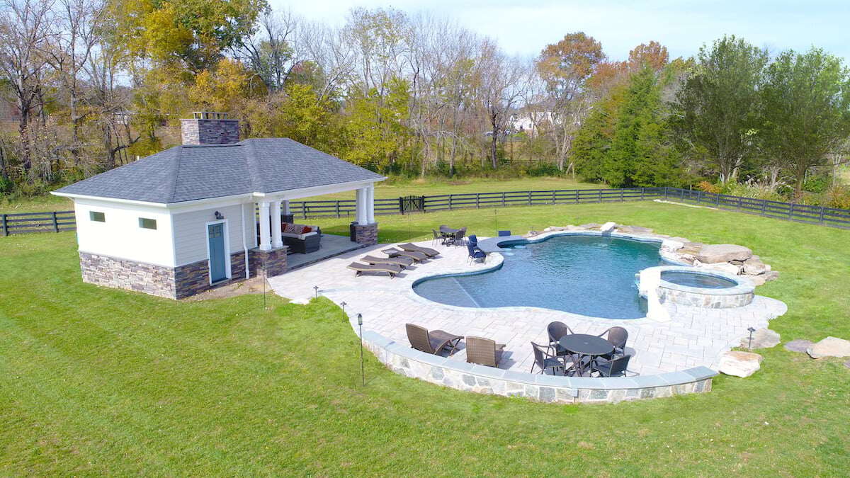 Covered pool house on patio and pavilion next to in ground pool