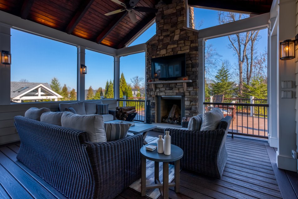 porch interior with vaulted ceilings and fan with TV mounted over fireplace