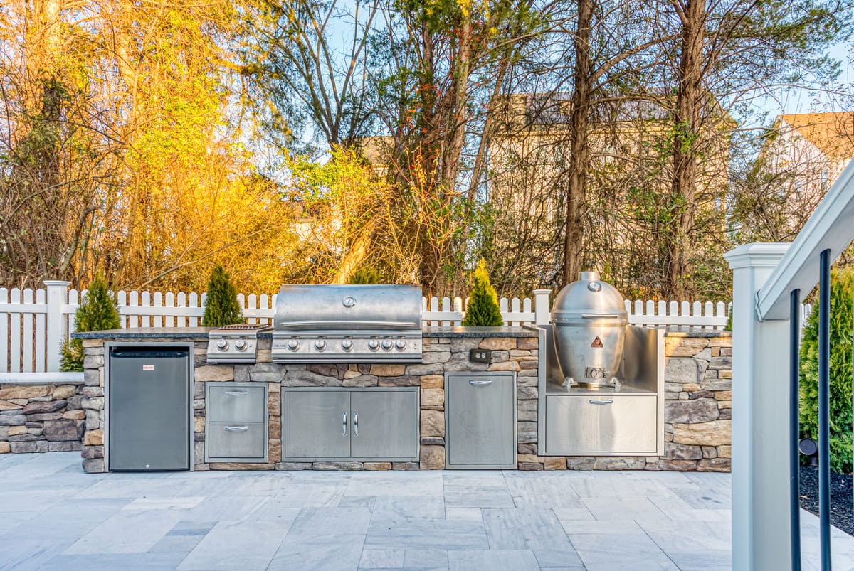 Outdoor kitchen on patio with built-in stainless steel appliances and storage