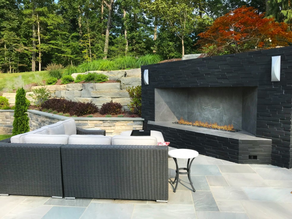 Fireplace with black modern surround on multi-level patio by Deckscapes of Virginia