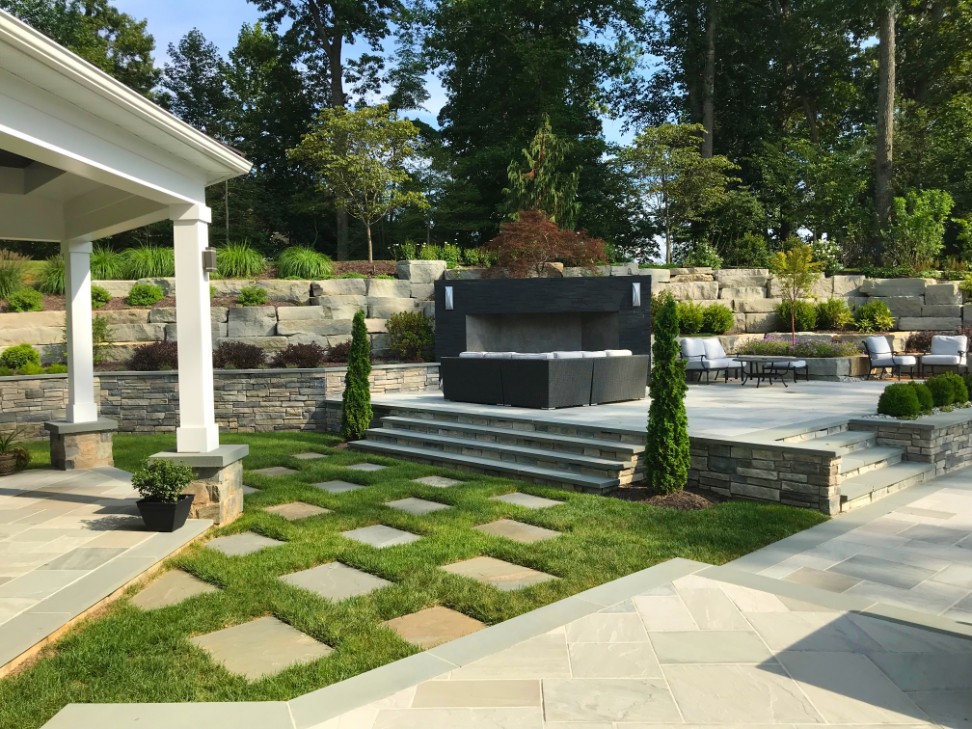 Multi-level patio design with Unilock pavers on sunny day by Deckscapes of Virginia