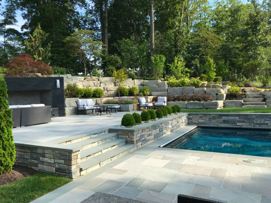 Multi-level paver patio and pool with stone pool grotto by Deckscapes of Virginia