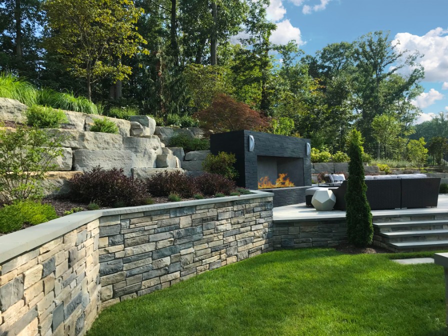 Retaining wall and boulders in landscaping design next to multi-level patio by Deckscapes of Virginia