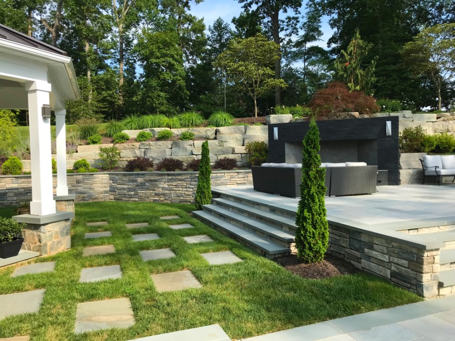 Stone pathway leading to steps of patio with view of retaining wall and landscaping by Deckscapes of Virginia