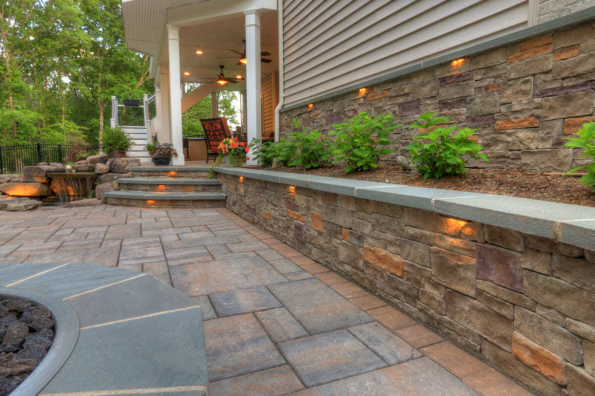 Paver patio and retaining wall with custom lighting by Deckscapes of VA