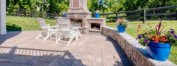 Paver patio with outdoor furniture and custom fireplace with log storage by Deckscapes of VA