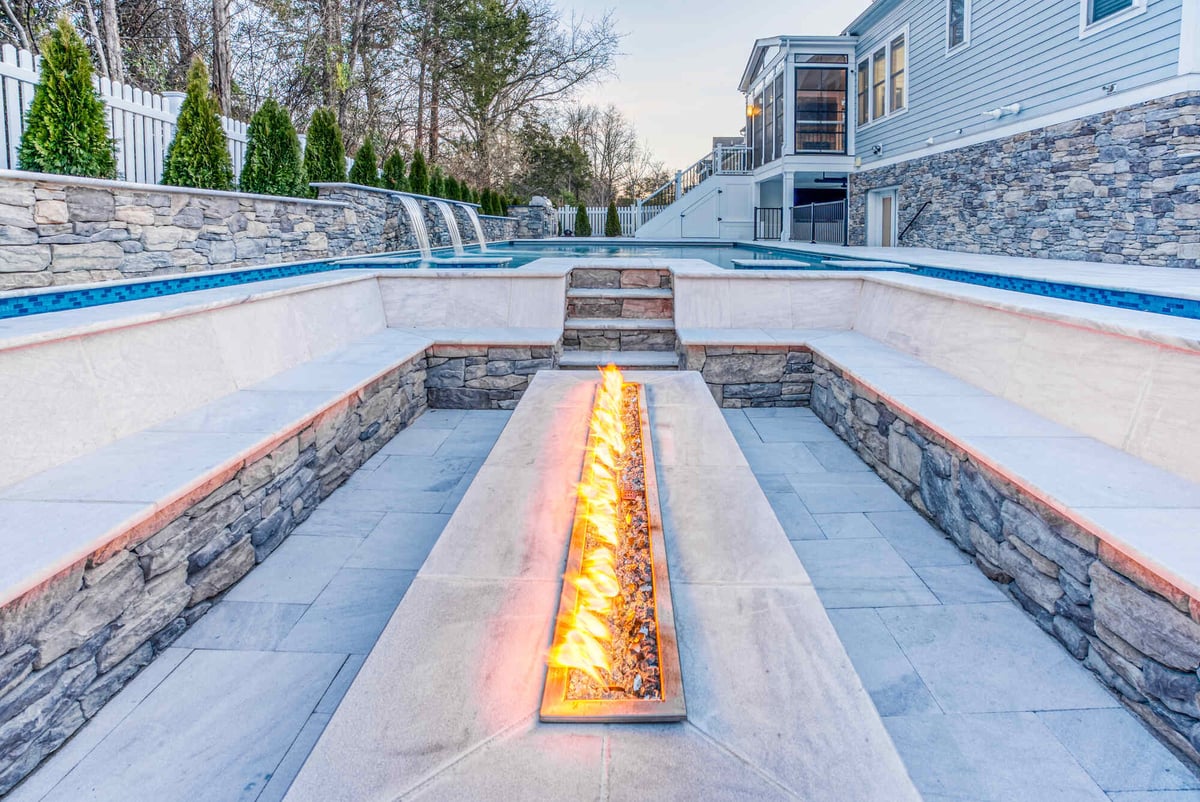 Rectangular fire pit in patio seating area next to gunite pool with sump system beneath in Northern Virginia-1