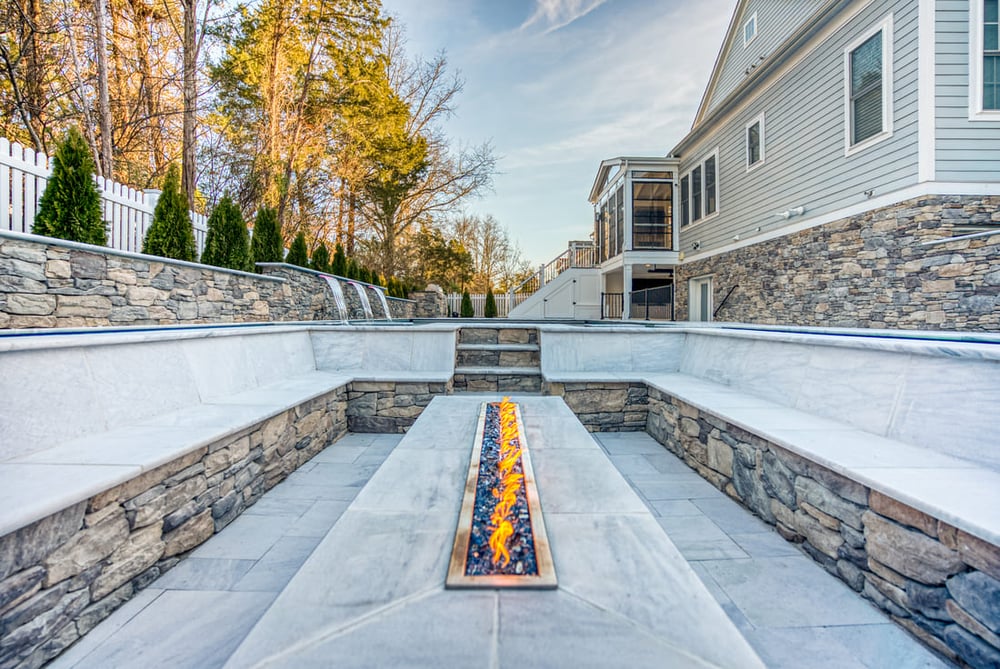 Rectangular fire pit in patio seating area next to gunite pool with sump system beneath in Northern Virginia