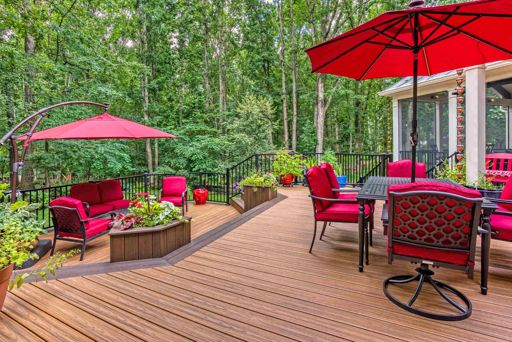 Red outdoor furniture and umbrella with potted plants on patio by Deckscapes of Virginia (1)