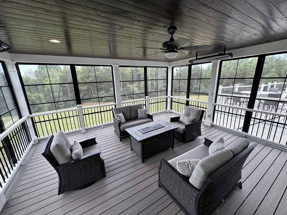 Screened-in porch with cushioned chairs and a modern table, designed by Deckscapes of Virginia