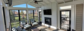 Screened-in porch with fireplace beneath mounted TV by Deckscapes of VA 