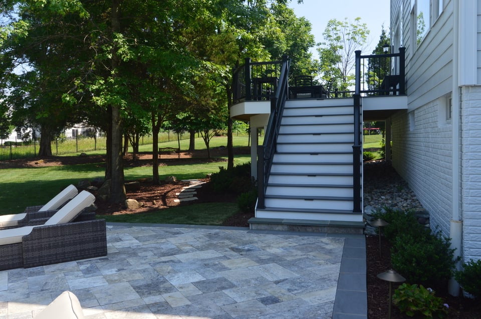View from the patio below a second-story deck with custom two-toned staircase by Deckscapes of Virginia