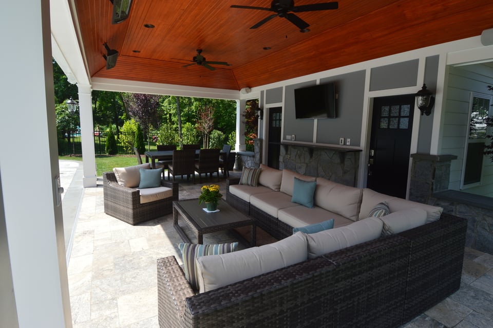 Wide view of a covered porch attached to a pool house with fan, tv, heaters, room for seating and dining, by Deckscapes of Virginia