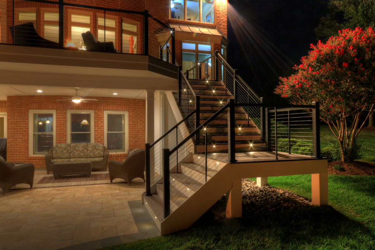 Steps with custom lighting leading to raised deck at night by Deckscapes of Virginia