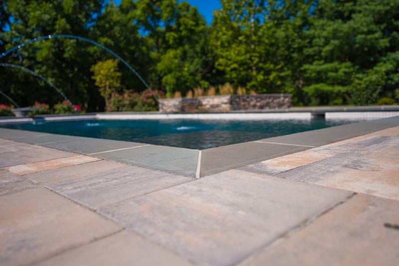 Up-close detail of stone pool coping on rectangular pool by Deckscapes of VA
